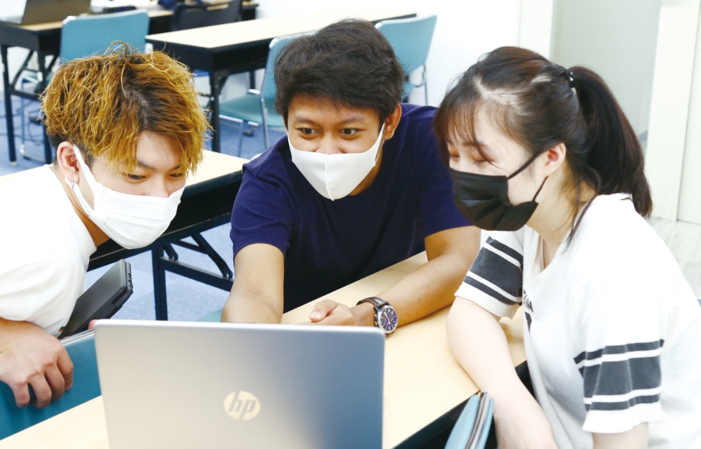 留学生と3人グループでパソコンを見ながらグループワークする様子