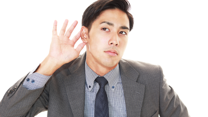 耳に手をあてて、耳を澄ましている男性。